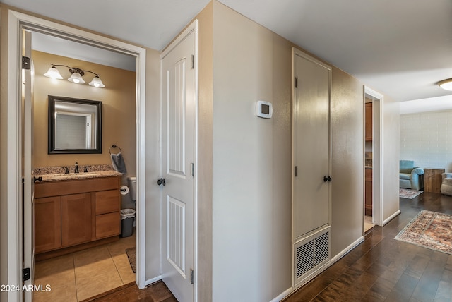 corridor with sink and dark tile patterned flooring