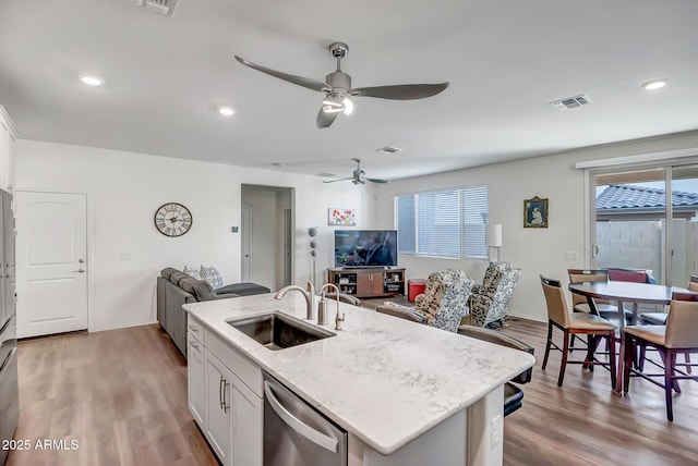 kitchen with sink, light hardwood / wood-style flooring, white cabinets, a center island with sink, and stainless steel dishwasher