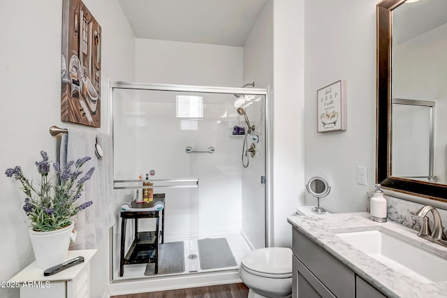 bathroom with hardwood / wood-style flooring, vanity, toilet, and walk in shower