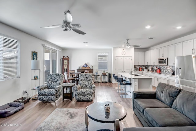 living room with ceiling fan, sink, and light hardwood / wood-style floors