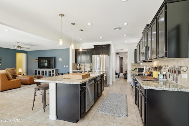 kitchen featuring light tile patterned floors, open floor plan, backsplash, a breakfast bar area, and freestanding refrigerator