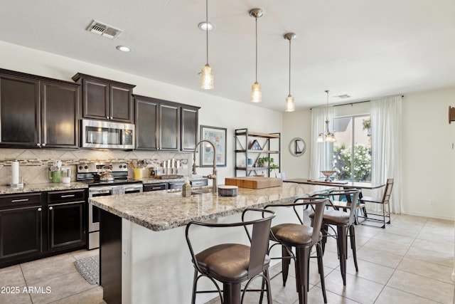 kitchen with appliances with stainless steel finishes, a sink, tasteful backsplash, light tile patterned flooring, and recessed lighting