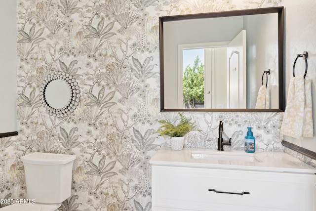 bathroom with wallpapered walls, toilet, and vanity