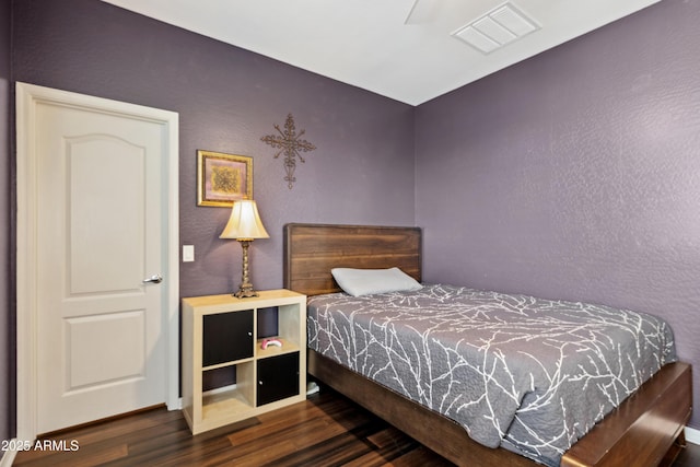 bedroom with wood finished floors, a textured wall, and baseboards
