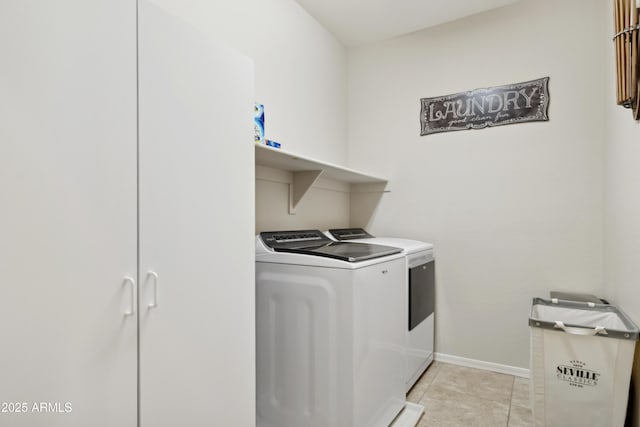 washroom featuring separate washer and dryer, baseboards, light tile patterned floors, and cabinet space