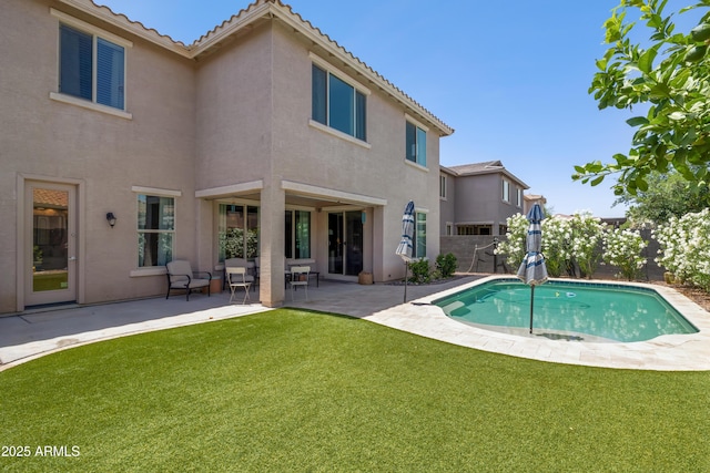 back of property with stucco siding, a patio, an outdoor pool, and a tile roof