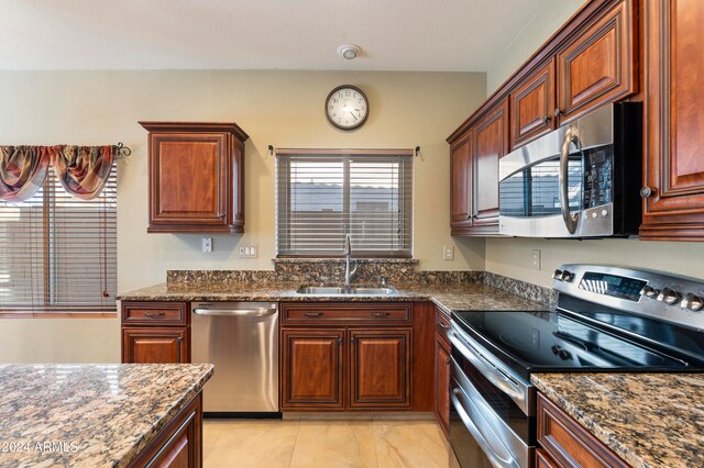 kitchen featuring stainless steel appliances, sink, dark stone counters, and light tile patterned floors