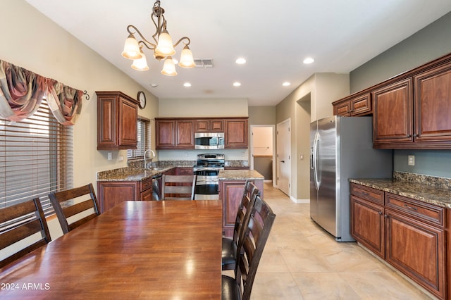 kitchen with a center island, appliances with stainless steel finishes, hanging light fixtures, and dark stone countertops