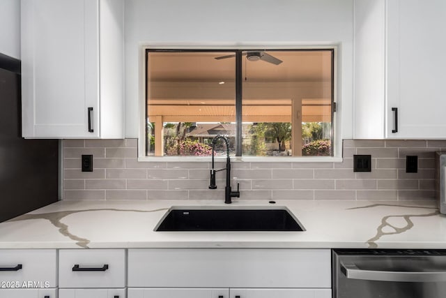 kitchen featuring sink, white cabinetry, stainless steel dishwasher, backsplash, and light stone countertops