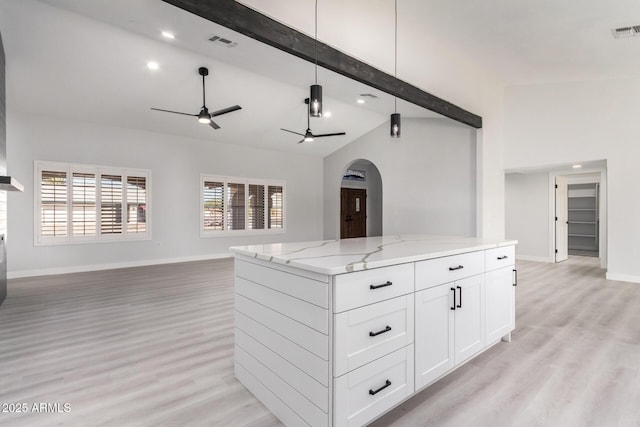 kitchen with ceiling fan, light stone counters, white cabinets, light hardwood / wood-style flooring, and decorative light fixtures