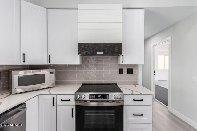 kitchen featuring white cabinets, appliances with stainless steel finishes, light stone countertops, and tasteful backsplash