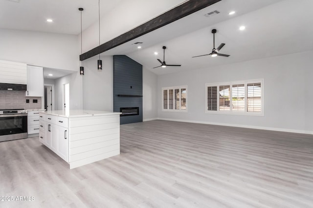 kitchen featuring a large fireplace, stainless steel electric range oven, white cabinets, and hanging light fixtures