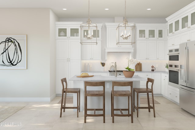 kitchen featuring backsplash, a center island with sink, white cabinets, and appliances with stainless steel finishes