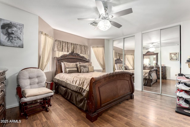 bedroom featuring multiple closets, ceiling fan, multiple windows, and hardwood / wood-style flooring