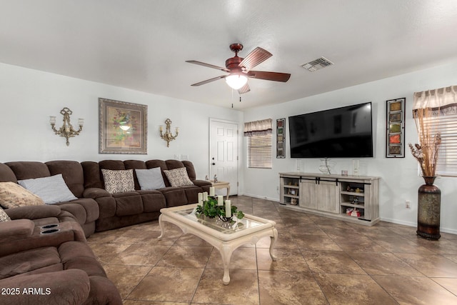 living room with ceiling fan and dark tile patterned floors