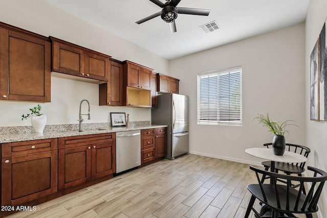 kitchen featuring ceiling fan, light hardwood / wood-style flooring, sink, stainless steel appliances, and light stone countertops