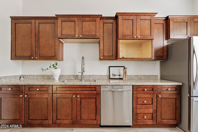 kitchen featuring stainless steel appliances, light stone countertops, light tile patterned flooring, and sink