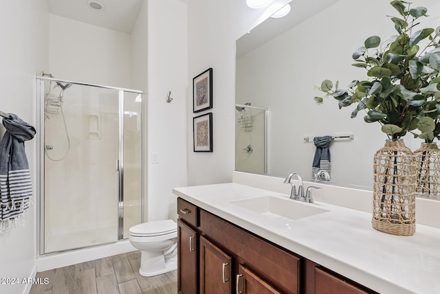 bathroom featuring hardwood / wood-style flooring, an enclosed shower, toilet, and vanity