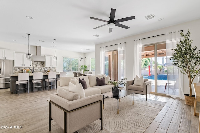 living room featuring ceiling fan with notable chandelier and light hardwood / wood-style floors