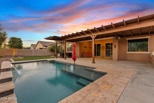 pool at dusk featuring pool water feature and a patio area