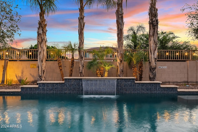 pool at dusk featuring pool water feature