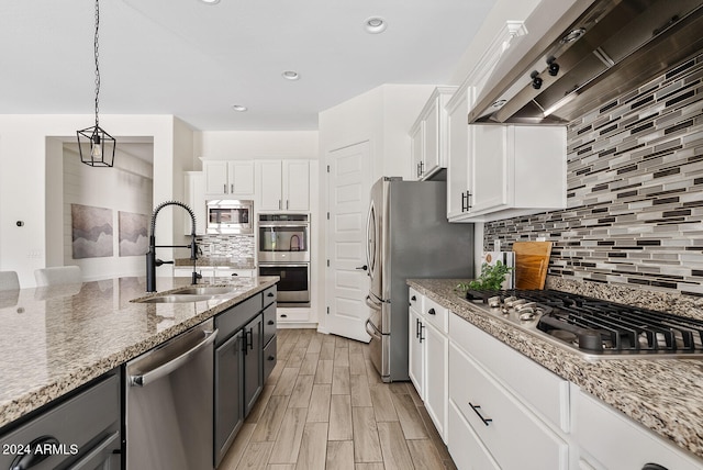 kitchen featuring pendant lighting, white cabinetry, appliances with stainless steel finishes, light stone countertops, and decorative backsplash