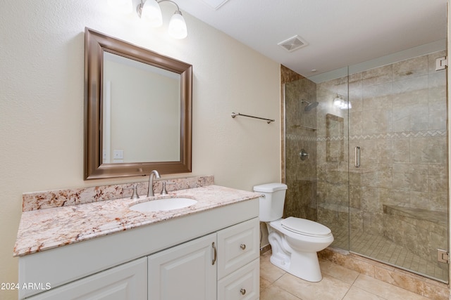 bathroom featuring toilet, tile patterned flooring, vanity, and a shower with door