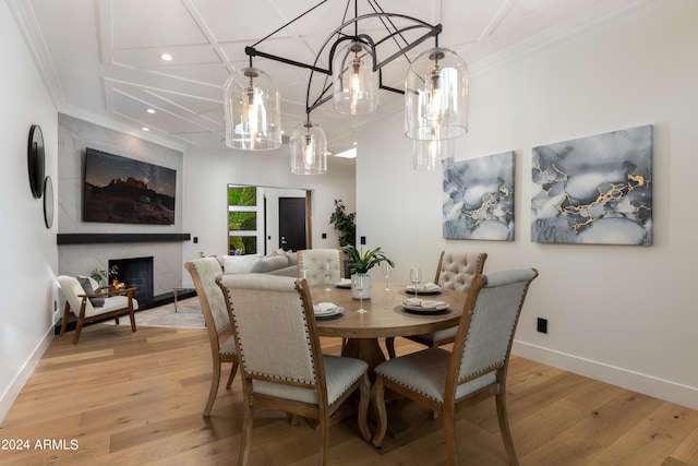 dining room with coffered ceiling, light hardwood / wood-style flooring, a fireplace, and crown molding