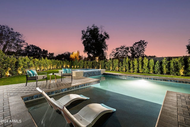 pool at dusk featuring a patio area and an in ground hot tub