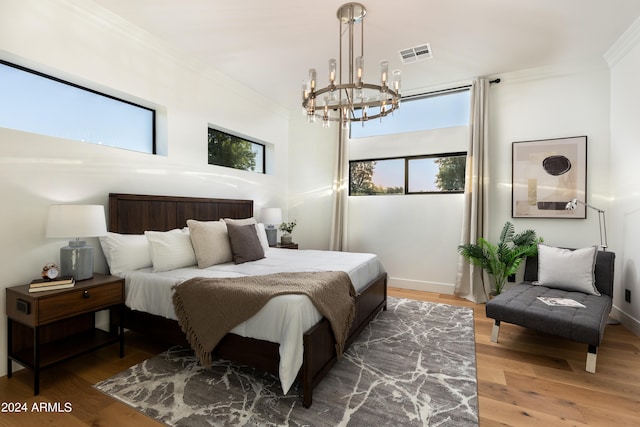 bedroom featuring a notable chandelier, ornamental molding, and hardwood / wood-style flooring