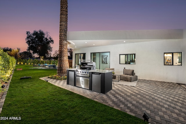 patio terrace at dusk with grilling area, a yard, and area for grilling