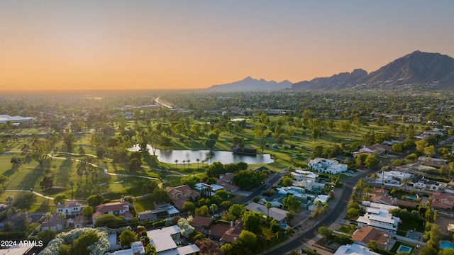 aerial view at dusk featuring a water and mountain view