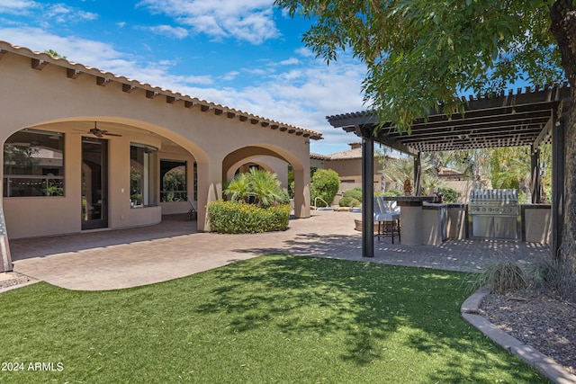 view of yard with an outdoor kitchen, ceiling fan, a pergola, and a patio