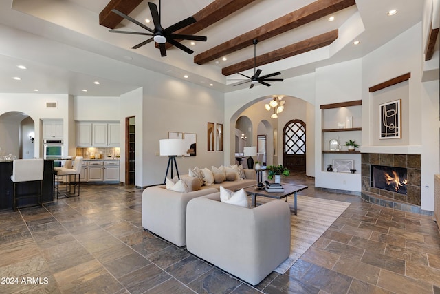 living room with ceiling fan, a fireplace, and a high ceiling