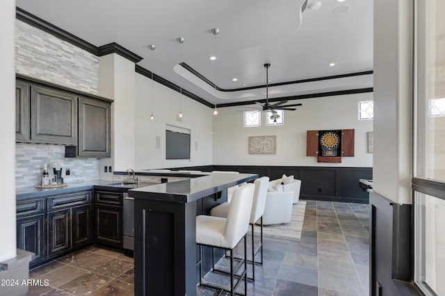 kitchen with a breakfast bar, sink, ceiling fan, plenty of natural light, and kitchen peninsula