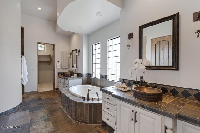 bathroom with vanity and a relaxing tiled tub