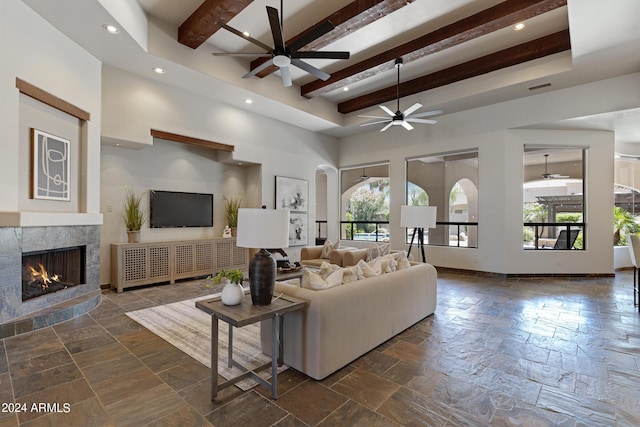 living room with ceiling fan, beam ceiling, and a tiled fireplace