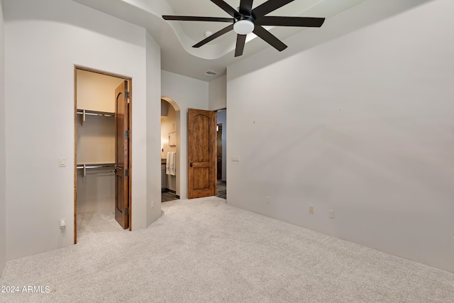 unfurnished bedroom with carpet flooring, ceiling fan, a spacious closet, and a closet