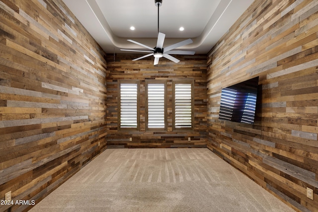 empty room with carpet flooring, ceiling fan, and wooden walls