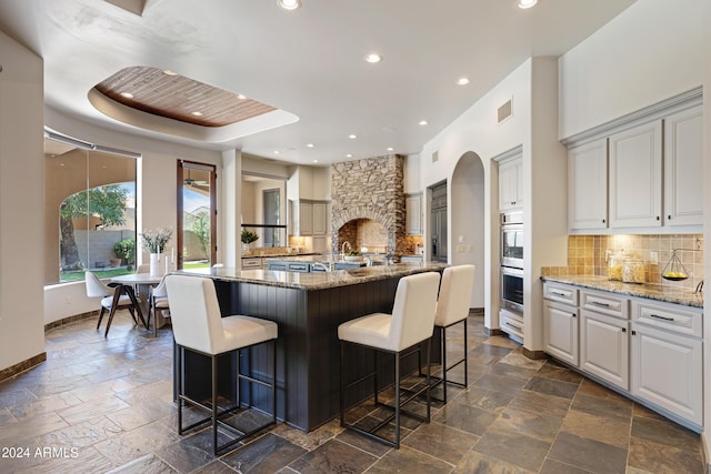 kitchen featuring light stone countertops, white cabinetry, a large island, and a breakfast bar area