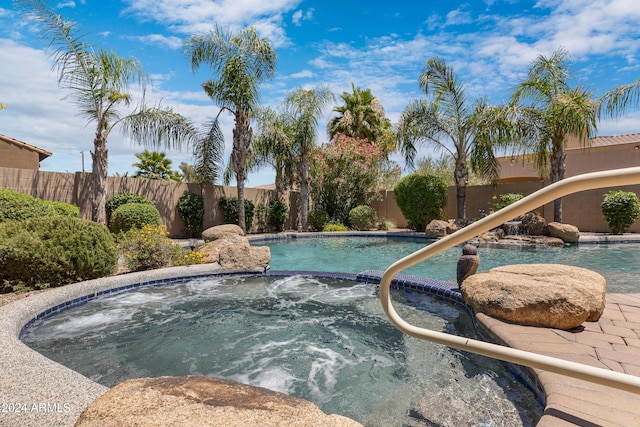 view of swimming pool featuring pool water feature and an in ground hot tub