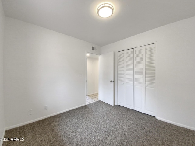 unfurnished bedroom featuring a closet, carpet flooring, baseboards, and visible vents