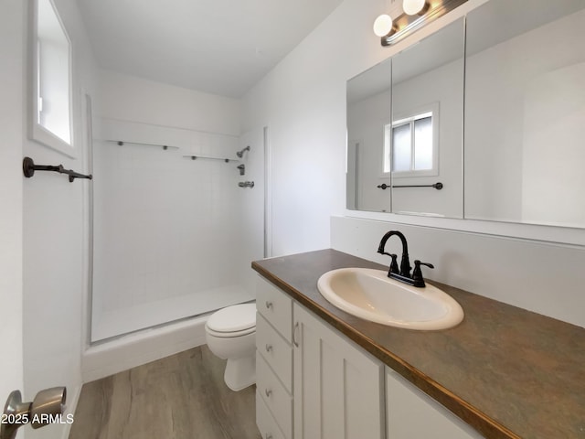 bathroom with a stall shower, toilet, vanity, and wood finished floors