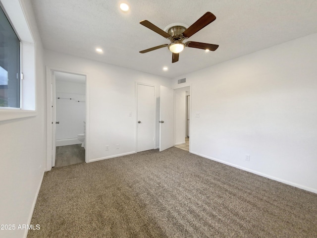 unfurnished bedroom featuring visible vents, baseboards, ensuite bathroom, and carpet