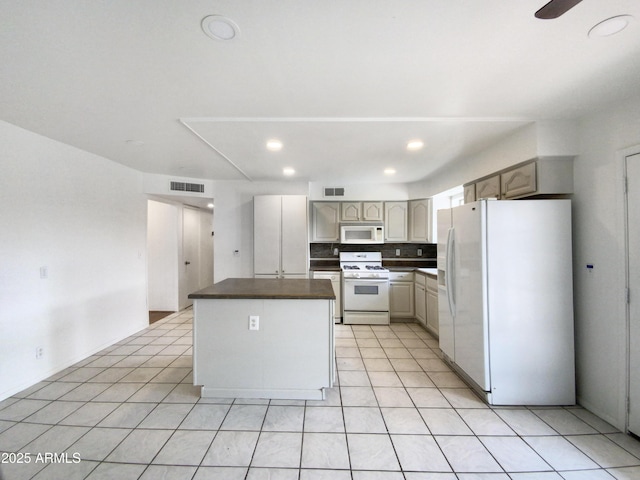 kitchen featuring white appliances, light tile patterned floors, dark countertops, and visible vents