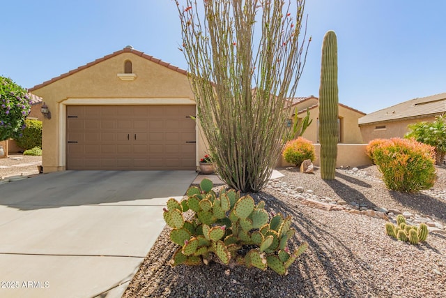 view of front of home featuring a tile roof, concrete driveway, a garage, and stucco siding