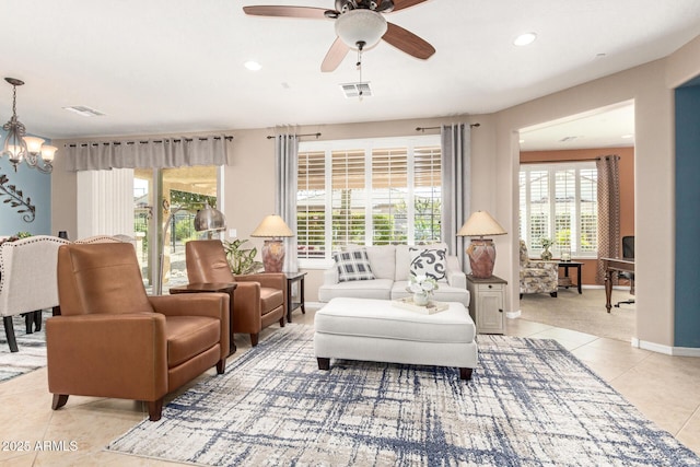 living room with light tile patterned floors, visible vents, baseboards, recessed lighting, and ceiling fan with notable chandelier