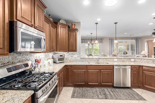 kitchen with a sink, brown cabinetry, light stone countertops, and stainless steel appliances