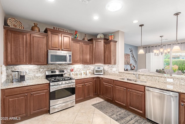 kitchen with a sink, stainless steel appliances, decorative backsplash, light stone countertops, and a chandelier