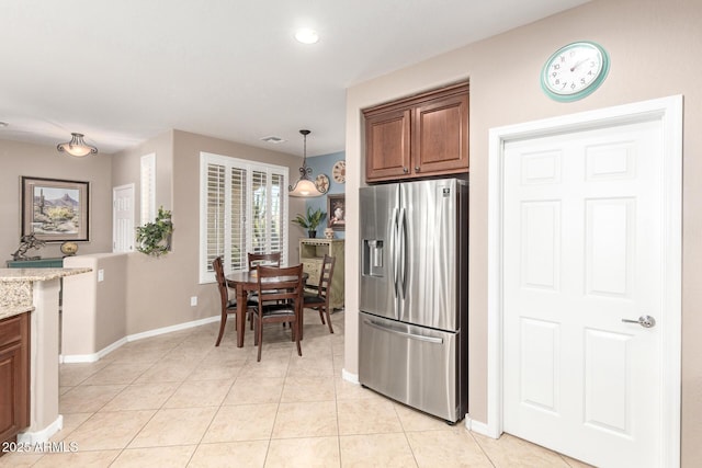 kitchen with light stone counters, brown cabinetry, visible vents, light tile patterned flooring, and stainless steel refrigerator with ice dispenser